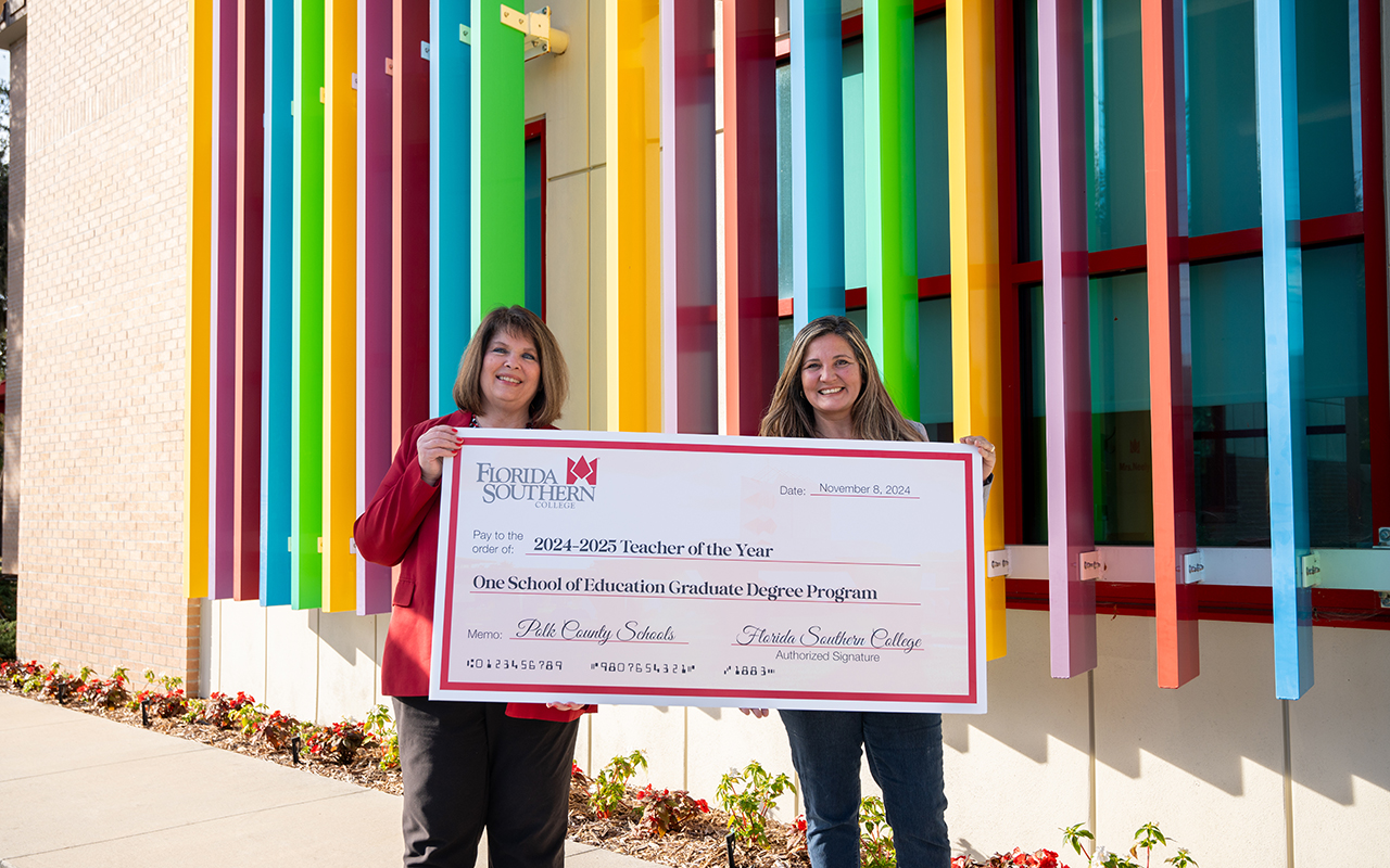 Cynara Appling and Dr. Rakes holding a large check for "One School of Education Graduate Degree Program