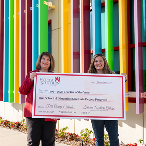 Cynara Appling and Dr. Rakes holding a large check for "One School of Education Graduate Degree Program