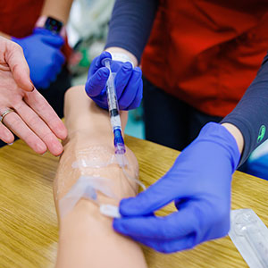 Nursing student using a syringe on a training dummy