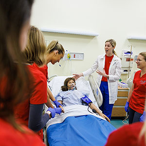 Nursing students with professor around training dummy